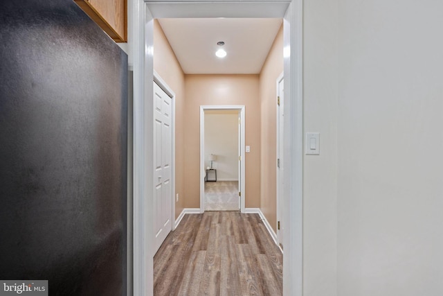 hallway featuring baseboards and wood finished floors