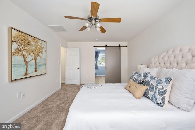 carpeted bedroom featuring baseboards, visible vents, ceiling fan, ensuite bathroom, and a barn door