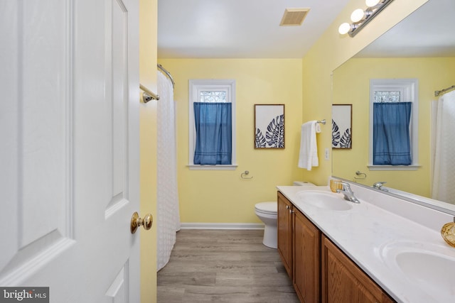 full bath featuring a sink, visible vents, toilet, and wood finished floors