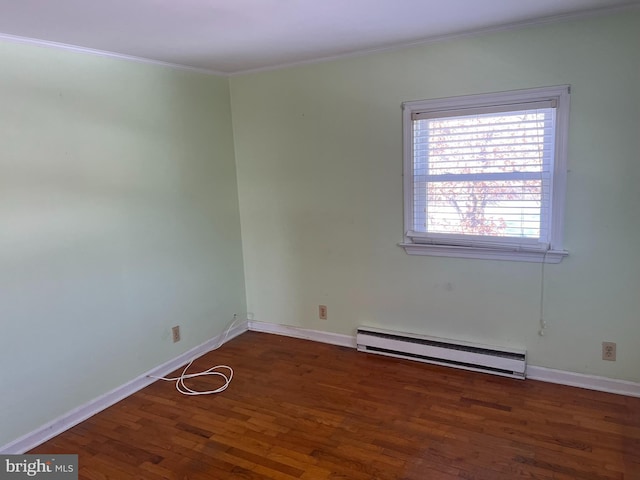 spare room featuring ornamental molding, baseboard heating, wood finished floors, and baseboards