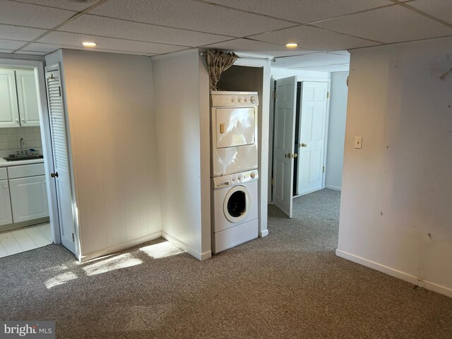 washroom with light colored carpet, stacked washer and dryer, laundry area, a sink, and baseboards