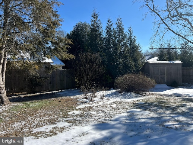 snowy yard with an outbuilding, fence, and a storage unit