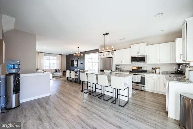 kitchen with a kitchen island, an inviting chandelier, a sink, stainless steel appliances, and open floor plan