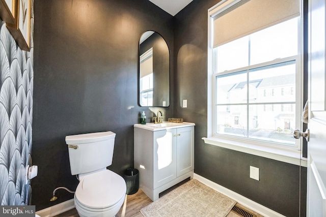 bathroom with vanity, wood finished floors, baseboards, visible vents, and toilet