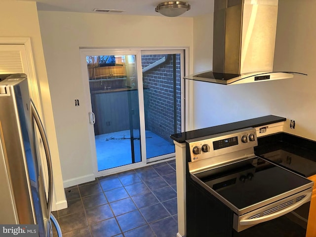 kitchen with wall chimney exhaust hood, stainless steel appliances, visible vents, dark tile patterned floors, and baseboards