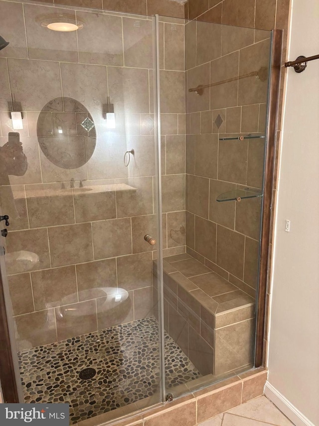 bathroom featuring a shower stall, baseboards, and tile patterned floors