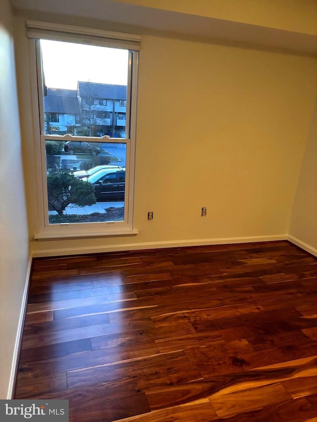 spare room with baseboards and wood finished floors