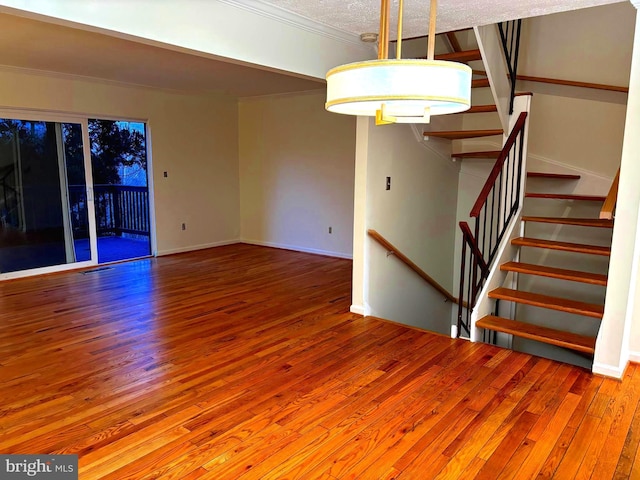 interior space featuring ornamental molding, baseboards, a textured ceiling, and hardwood / wood-style floors