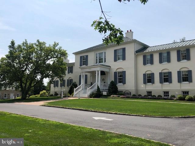 colonial inspired home featuring a standing seam roof, stucco siding, metal roof, and a front yard