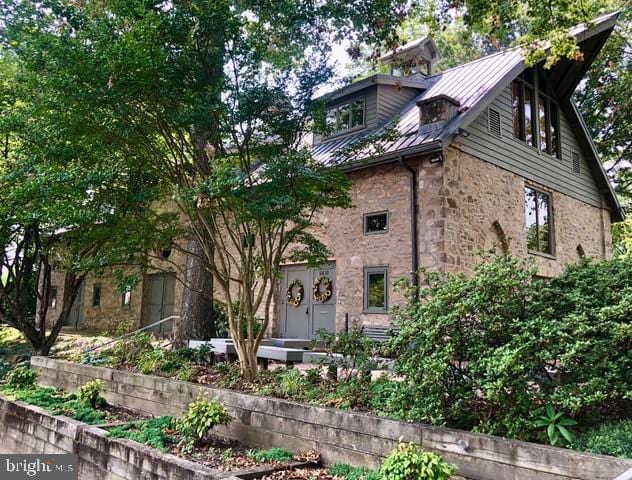 view of front of house featuring stone siding, metal roof, and a standing seam roof