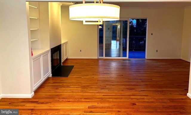 interior space with built in shelves, baseboards, and wood finished floors