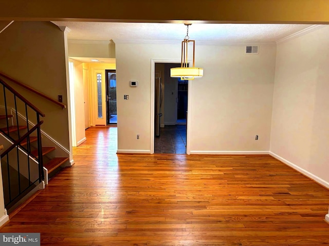 unfurnished dining area with wood finished floors, visible vents, crown molding, and stairs