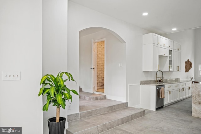 kitchen featuring arched walkways, recessed lighting, a sink, white cabinets, and stainless steel dishwasher