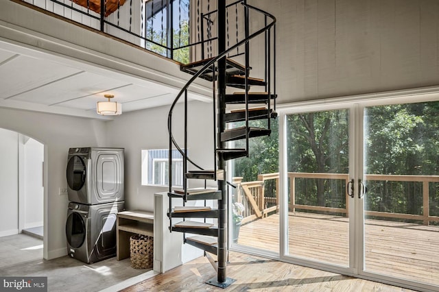 stairs featuring arched walkways, baseboards, and stacked washing maching and dryer