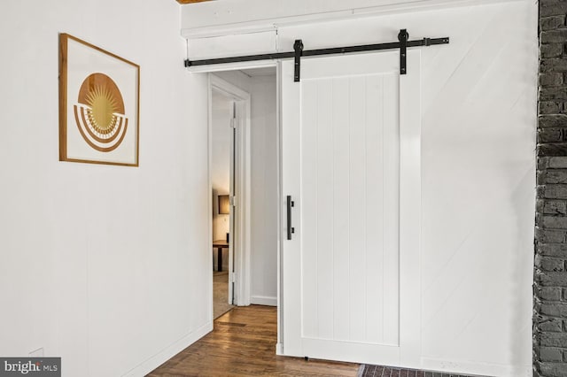 interior space with dark wood-type flooring, baseboards, and a barn door