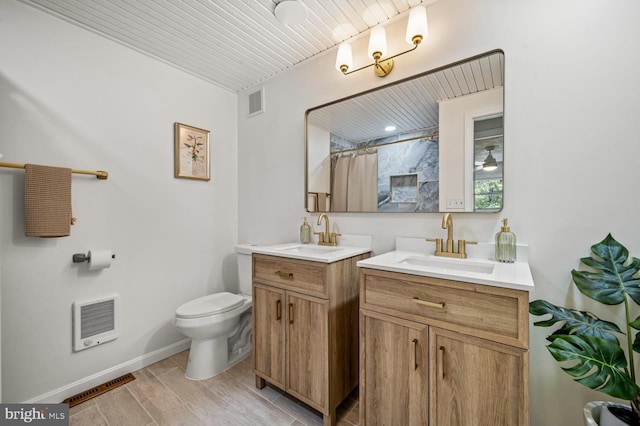 full bath featuring toilet, visible vents, a sink, and heating unit