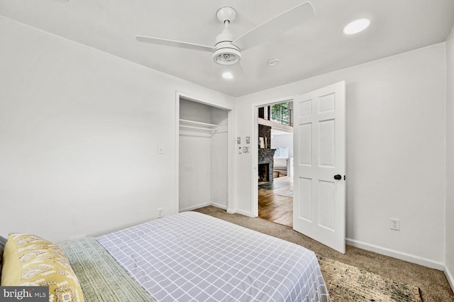 bedroom featuring carpet floors, a fireplace, a ceiling fan, baseboards, and a closet