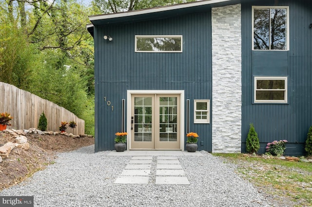 exterior space featuring stone siding, french doors, and fence