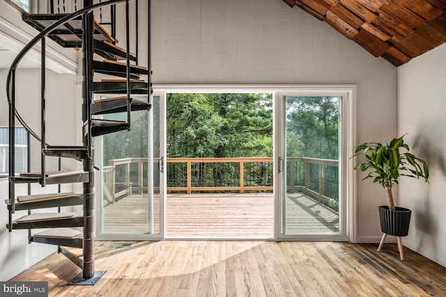 doorway featuring lofted ceiling, wood finished floors, stairs, and baseboards