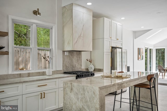 kitchen featuring freestanding refrigerator, a healthy amount of sunlight, decorative backsplash, and light stone countertops