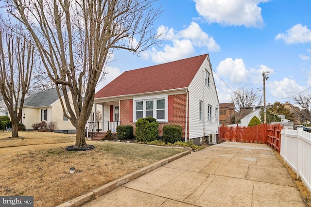 view of front facade with concrete driveway, fence, brick siding, and a front lawn