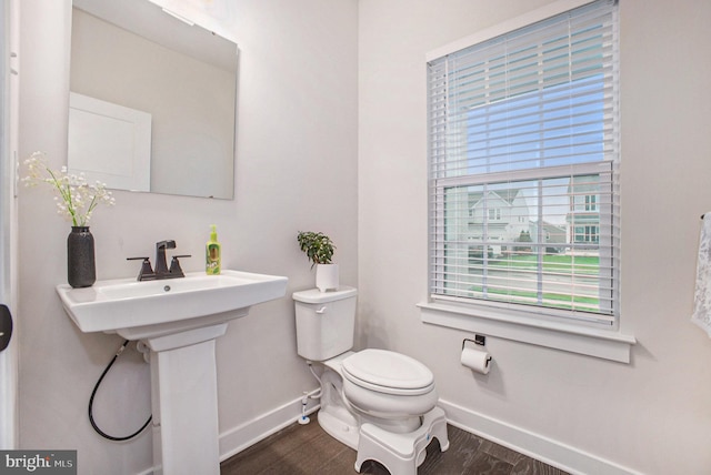 half bath featuring toilet, baseboards, and wood finished floors