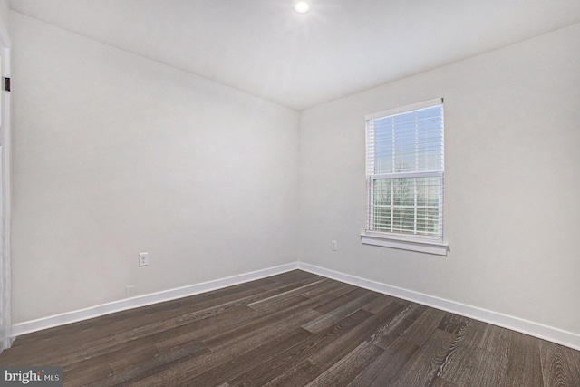 empty room with dark wood finished floors and baseboards