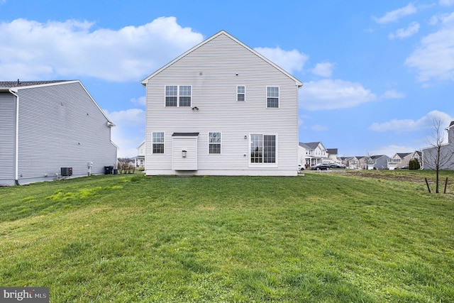 rear view of house featuring cooling unit and a yard