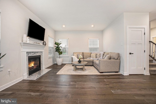 living area featuring a fireplace, stairway, baseboards, and wood finished floors