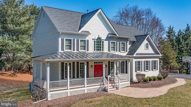 view of front facade featuring covered porch, metal roof, a shingled roof, and a standing seam roof