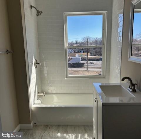 bathroom with baseboards, shower / washtub combination, a wealth of natural light, and vanity