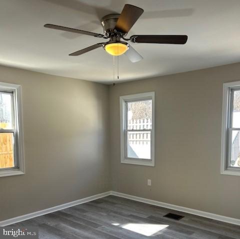 spare room with visible vents, baseboards, and dark wood-style flooring