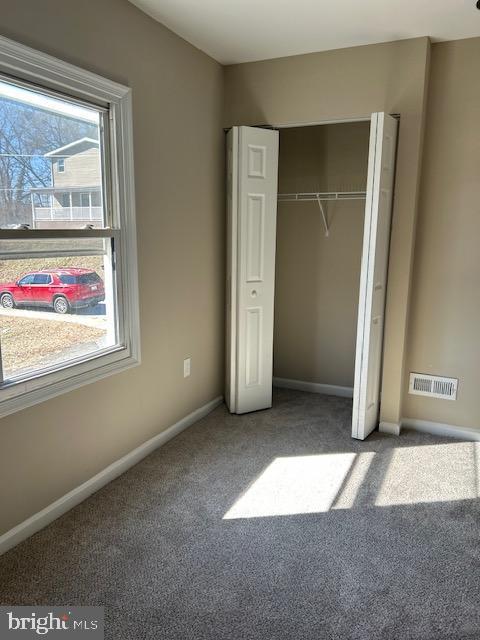 unfurnished bedroom with carpet, a closet, visible vents, and baseboards