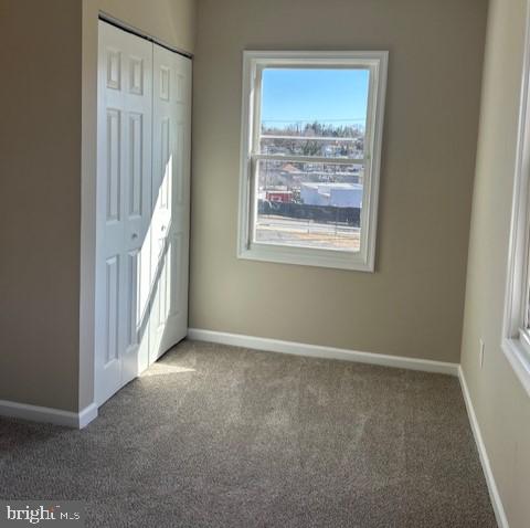 unfurnished bedroom with a closet, carpet flooring, and baseboards