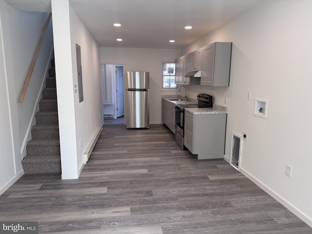 kitchen featuring dark wood finished floors, a baseboard radiator, stainless steel appliances, gray cabinetry, and a sink