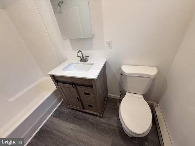 bathroom with a tub to relax in, toilet, wood finished floors, vanity, and a baseboard heating unit