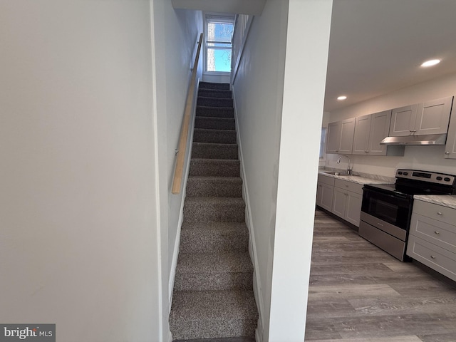 stairs with recessed lighting, wood finished floors, and baseboards