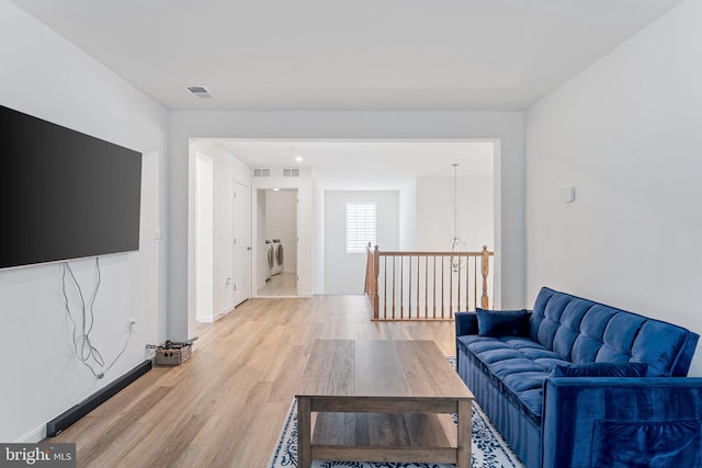 living room featuring light wood-style flooring, visible vents, and washing machine and dryer