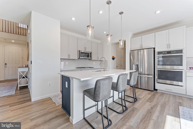 kitchen featuring light countertops, appliances with stainless steel finishes, a sink, and light wood-style floors