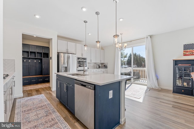 kitchen featuring light countertops, appliances with stainless steel finishes, light wood-style floors, white cabinetry, and a sink