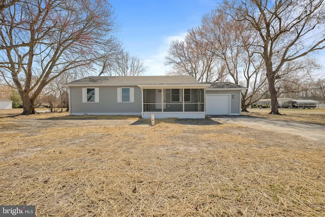 ranch-style house featuring concrete driveway, an attached garage, and a sunroom