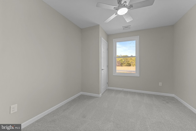 spare room featuring a ceiling fan, light colored carpet, visible vents, and baseboards