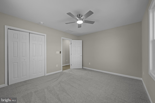 unfurnished bedroom with carpet, baseboards, ceiling fan, and a closet