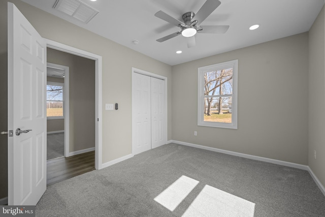 unfurnished bedroom with carpet floors, multiple windows, visible vents, and baseboards