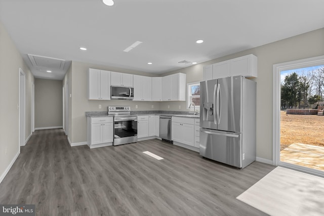 kitchen with appliances with stainless steel finishes, white cabinetry, and a healthy amount of sunlight