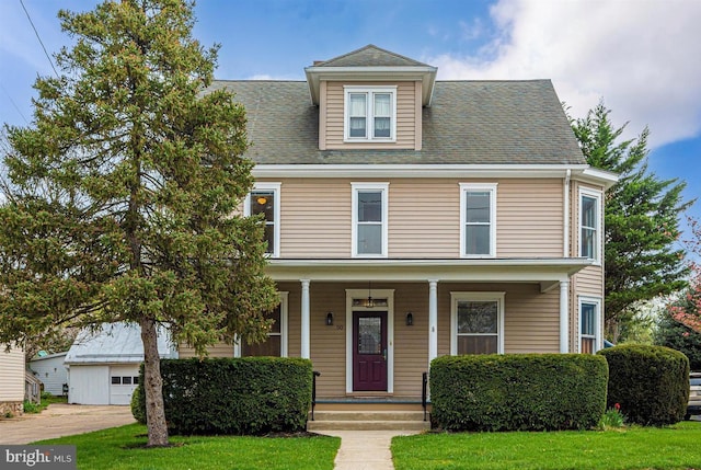 american foursquare style home with roof with shingles, a porch, and a front lawn