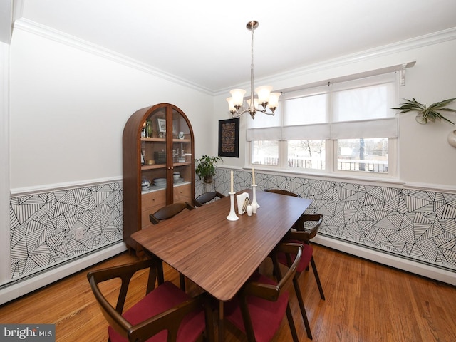 dining space featuring a baseboard heating unit, a chandelier, crown molding, and wood finished floors