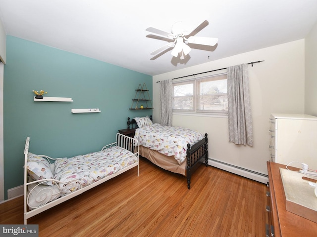 bedroom featuring a baseboard radiator, wood finished floors, and a ceiling fan