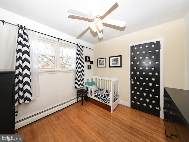 bedroom featuring a baseboard heating unit, a ceiling fan, and wood finished floors