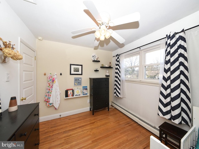 misc room with light wood-style floors, a baseboard radiator, baseboards, and a ceiling fan